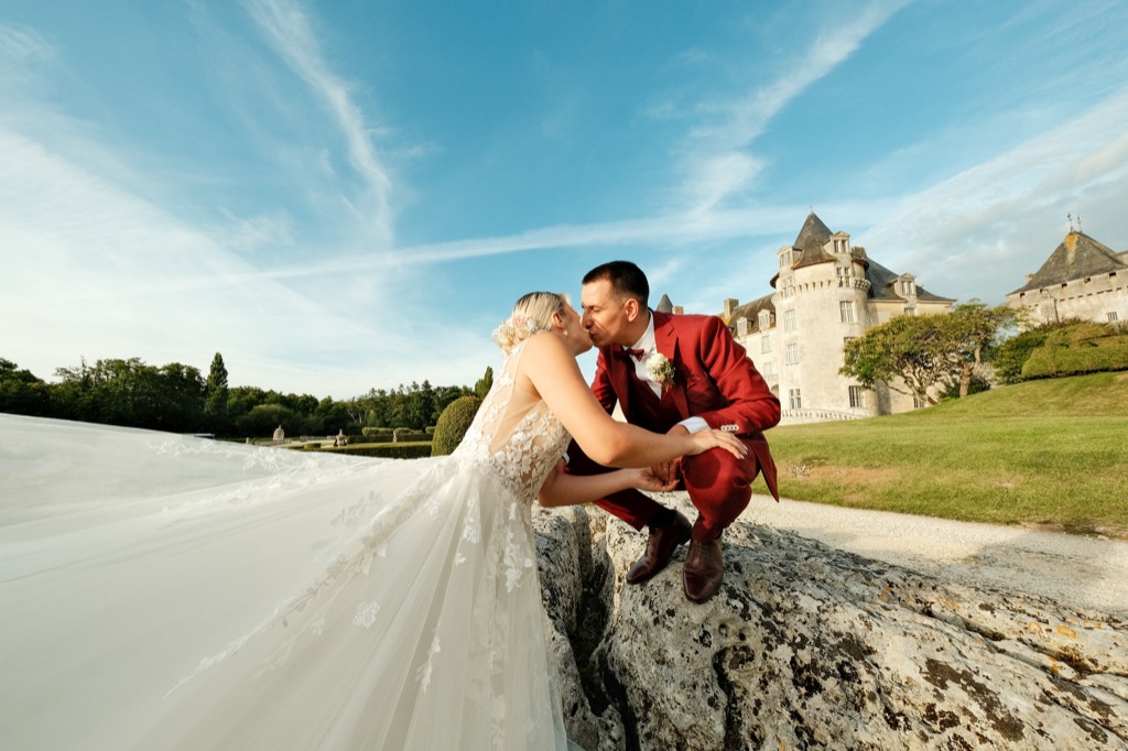 Photographe mariage Charente-Maritime — couple au château, robe envolée par le vent