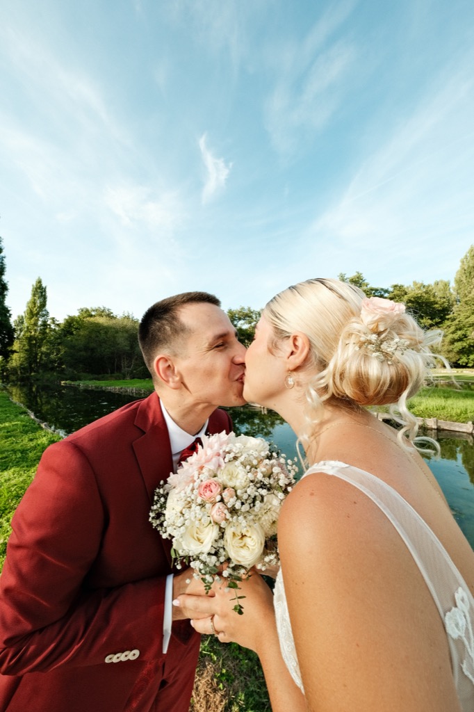 Photographe mariage Nouvelle-Aquitaine — baiser sous le bouquet, ciel bleu